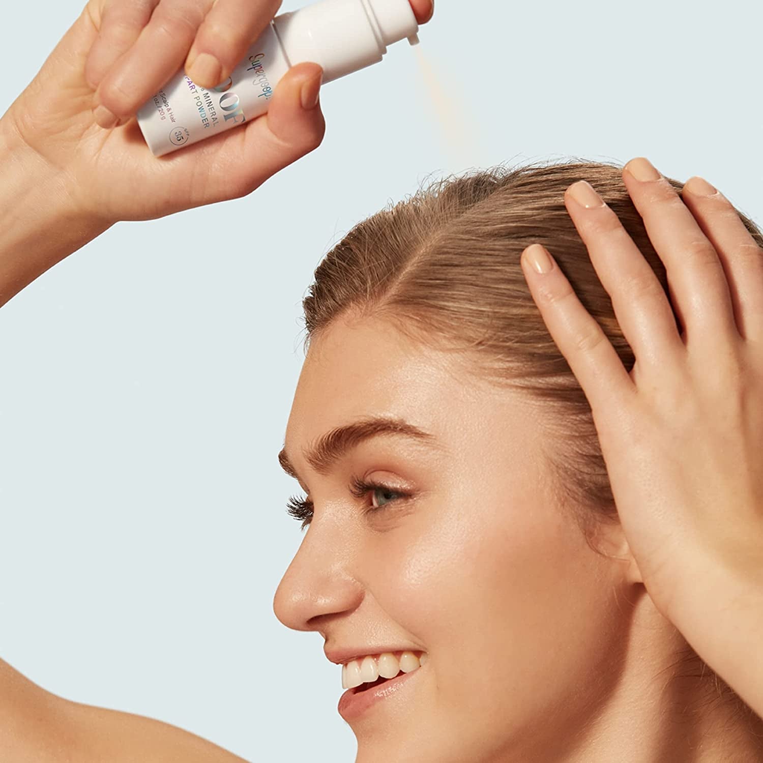 model applying Supergoop mineral part powder to scalp