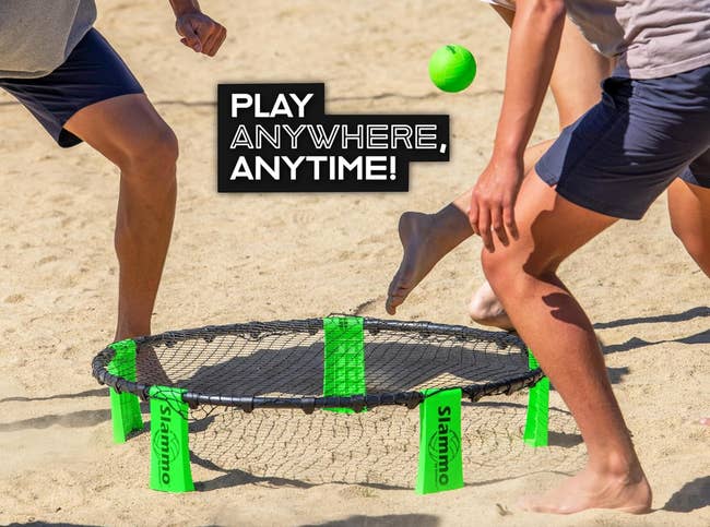 People playing a formation  crippled  with a circular  nett  connected  the sand. The substance   reads, 
