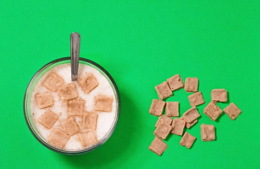 a glass bowl with candle wax to look like cinnamon toast crunch cereal and milk, with a spoon on the side