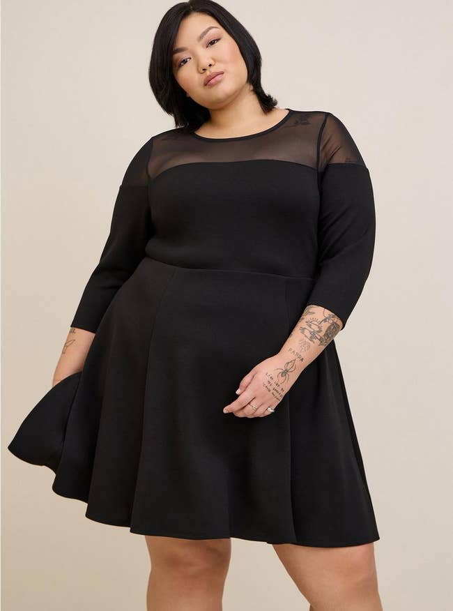 plus size model in pleated dress with mesh shoulders and quarter length sleeves