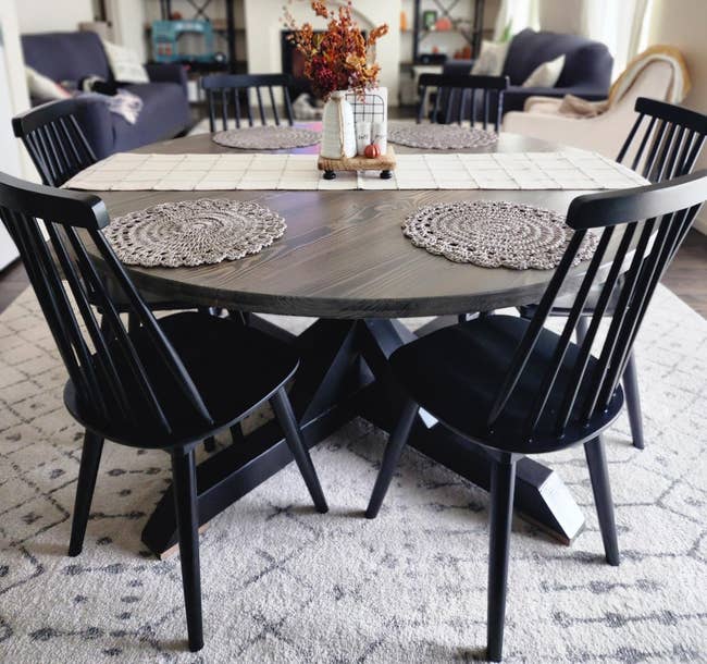 Round dining table field with four chairs, placemats, and a centerpiece, in a living room setting