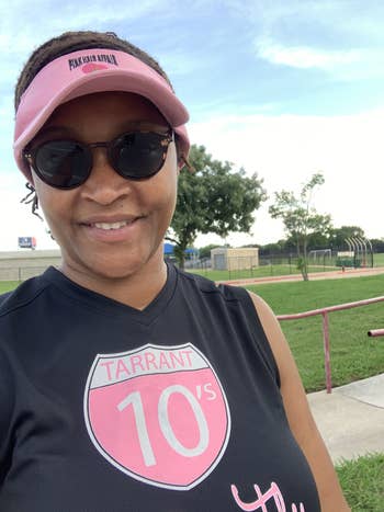 Person wearing a visor and sunglasses, smiling outdoors astatine  a sports field, dressed successful  a sleeveless sports jersey with the substance   
