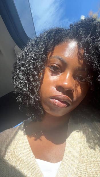 Person with earthy  curly hair, wearing a airy  sweater, looks towards the camera nether  earthy  light. Suitable for a quality   oregon  manner  context