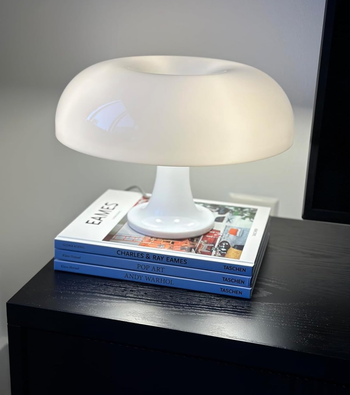 white mushroom lamp atop a stack of magazines on a nightstand