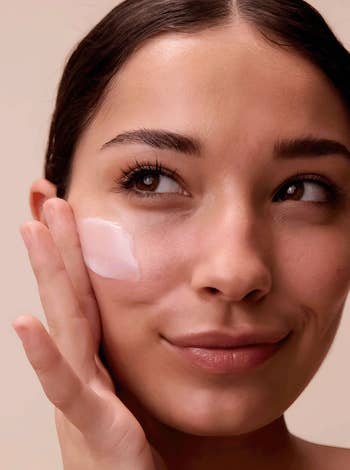 Person applying skincare pick  to their look   with a thoughtful expression