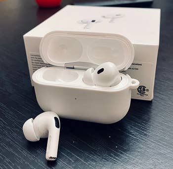 reviewer photo of one airpod in its charging case and one airpod next to the charging case