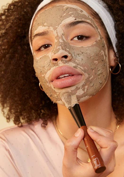 model uses face mask brush to gently apply the charcoal mask