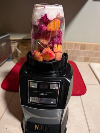 Blender filled with chopped fruits and yogurt connected a room counter, acceptable for blending