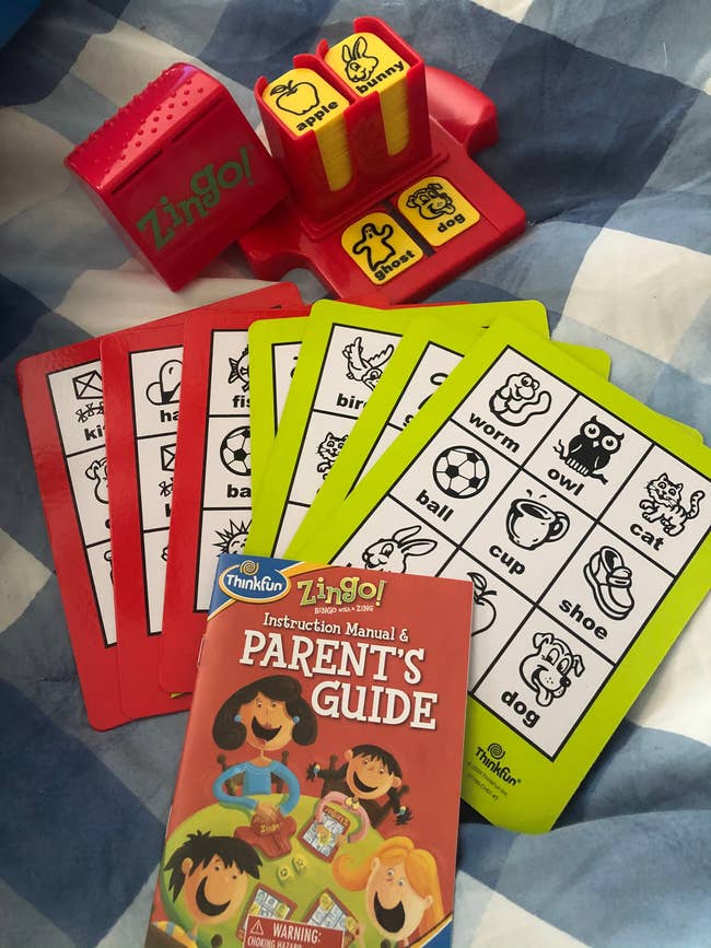 Zingo game set with red and yellow Zingo! dispenser, red and green cards with images, and a