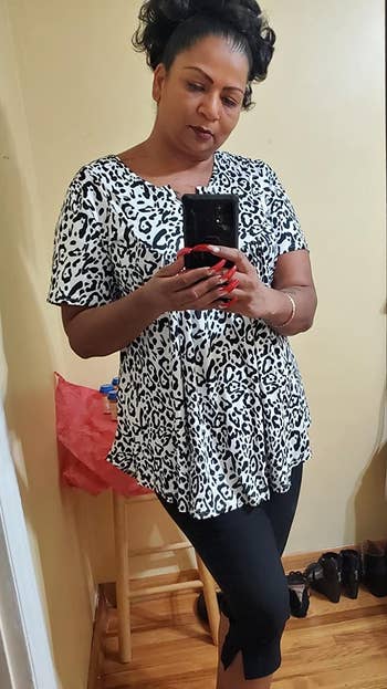 reviewer wearing the black and white print top with black pants