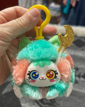 Plush keychain featuring a cute feline  look   with starry eyes, fluffy teal fur, and crescent satellite  detail