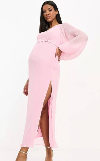 model posing wearing one sleeve pink dress with slit and belt