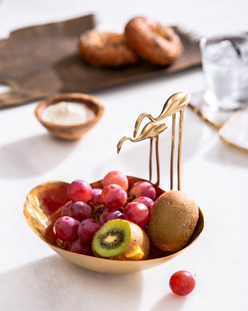 small bowl with flamingo sculptures on side holding grapes and kiwis
