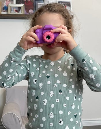 A child holding up the camera to their eyes to take a picture