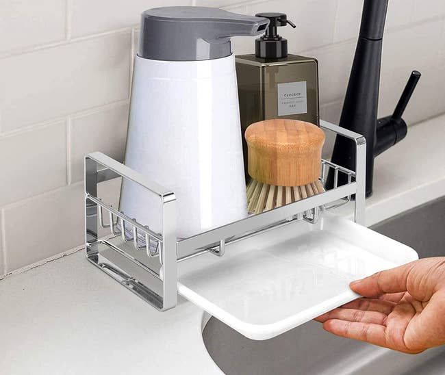 a hand pulling the drip drawer out from under the sink caddy