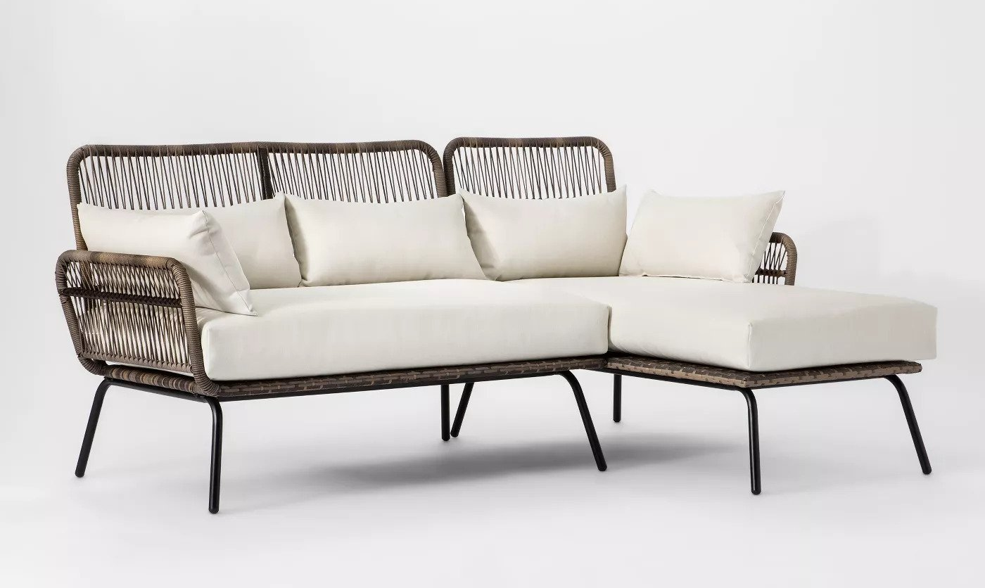 wicker-backed sofa with cream cushions in an L-shape 
