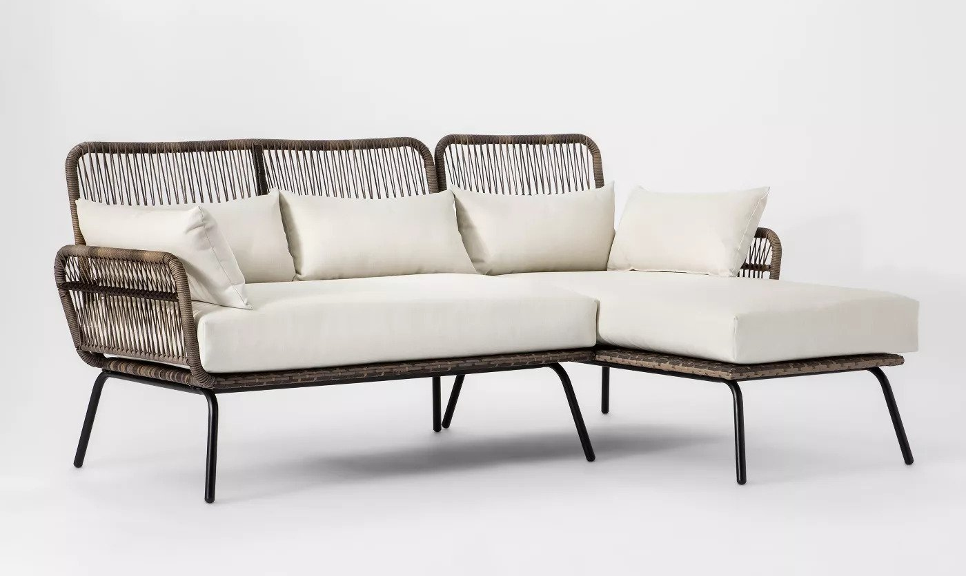 wicker-backed sofa with cream cushions in an L-shape