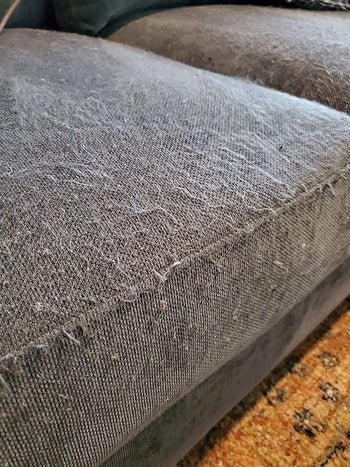 reviewer before image of a gray couch cushion covered in pilling and matted fibers