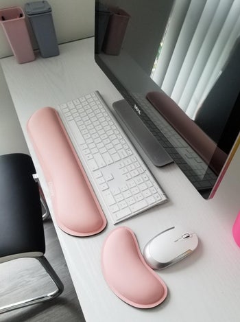 reviewer's pink keyboard and mouse rest at their computer desk 