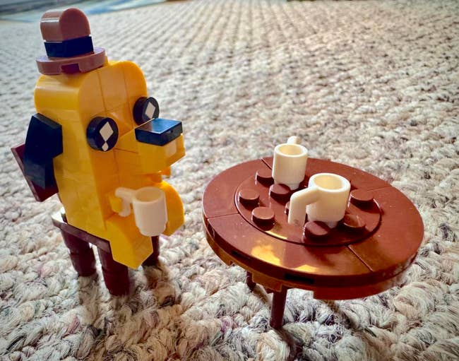 Cartoon-style artifact  fig  adjacent  to tiny  ceramic  array  with 2  mugs connected  a textured surface