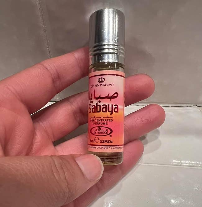 Hand holding a roll-on vessel of Sabaya concentrated perfume