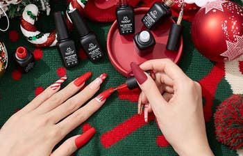model applying the red polish to their nails with the six bottles in the background