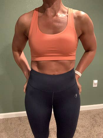reviewer wearing the sports bra in orange showing the front