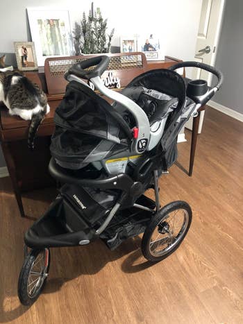 a reviewer photo of the carseat on top of the jogging stroller in the color black