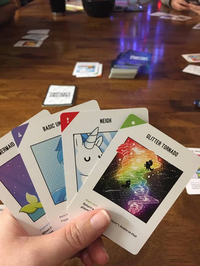 image of reviewer's hand holding several unstable unicorn cards
