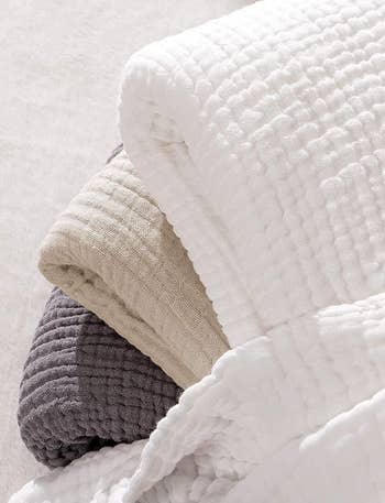 stack of tan, white, and grey throws