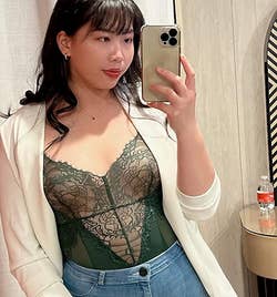 reviewer in a mirror selfie wearing a blazer, lace top, and jeans