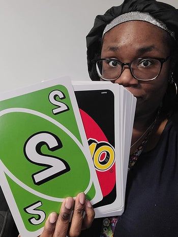 a reviewer holding a hand of the giant uno cards