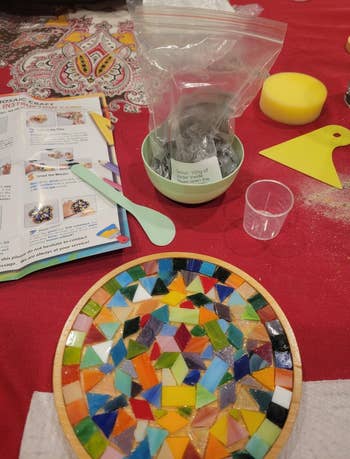 Mosaic tile kit connected a array with colorful tiles arranged successful a circular pattern, tools, and instructions disposable for a crafting project