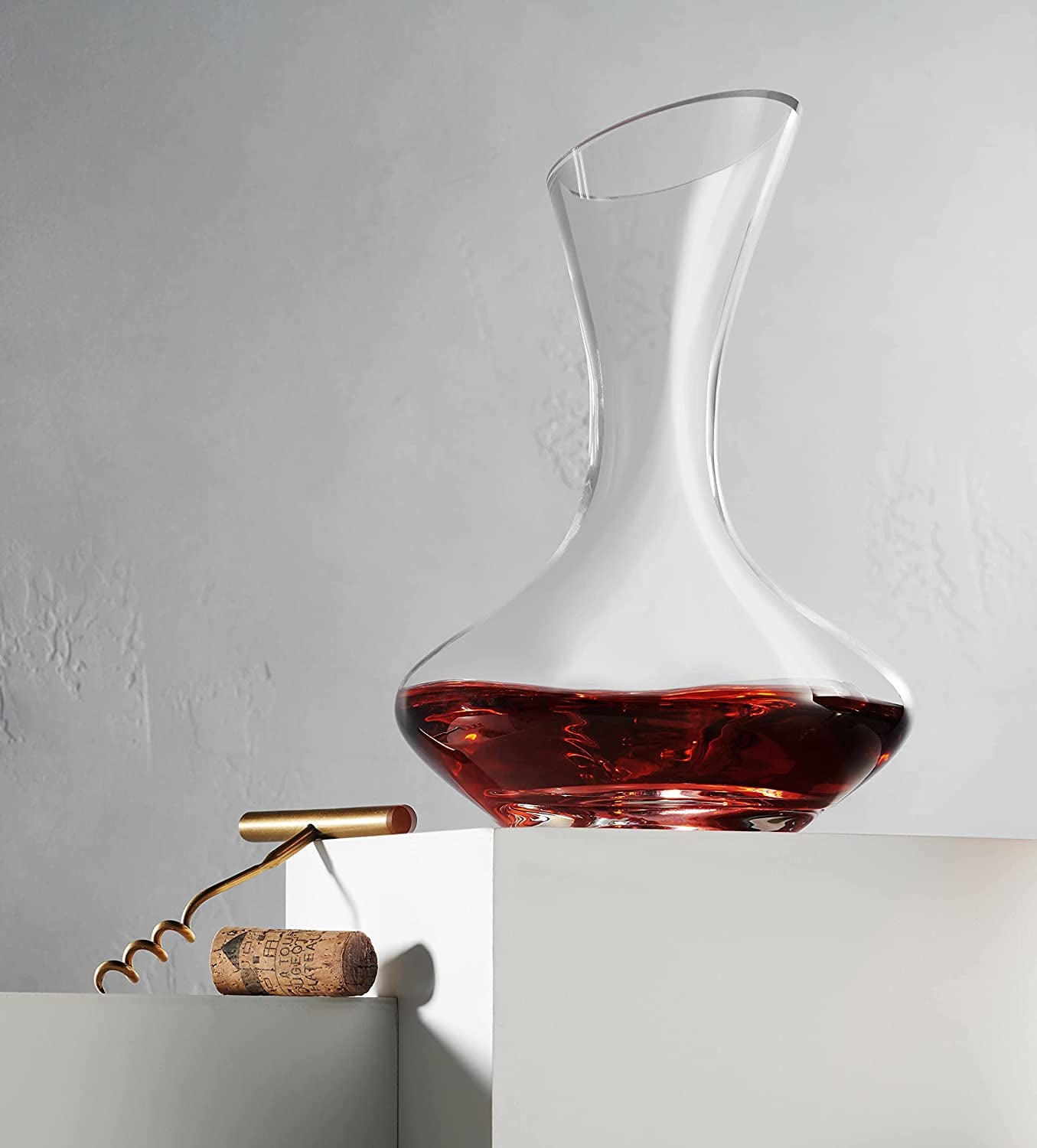 A curved clear wine aerator with red wine in it