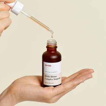 model holding a dropper and a bottle of Manyo Bifida Biome Complex Ampoule