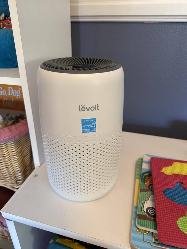 Air purifier connected a support adjacent to children’s books and puzzles