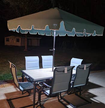 a reviewer photo of the light shining down on an outdoor table at night 