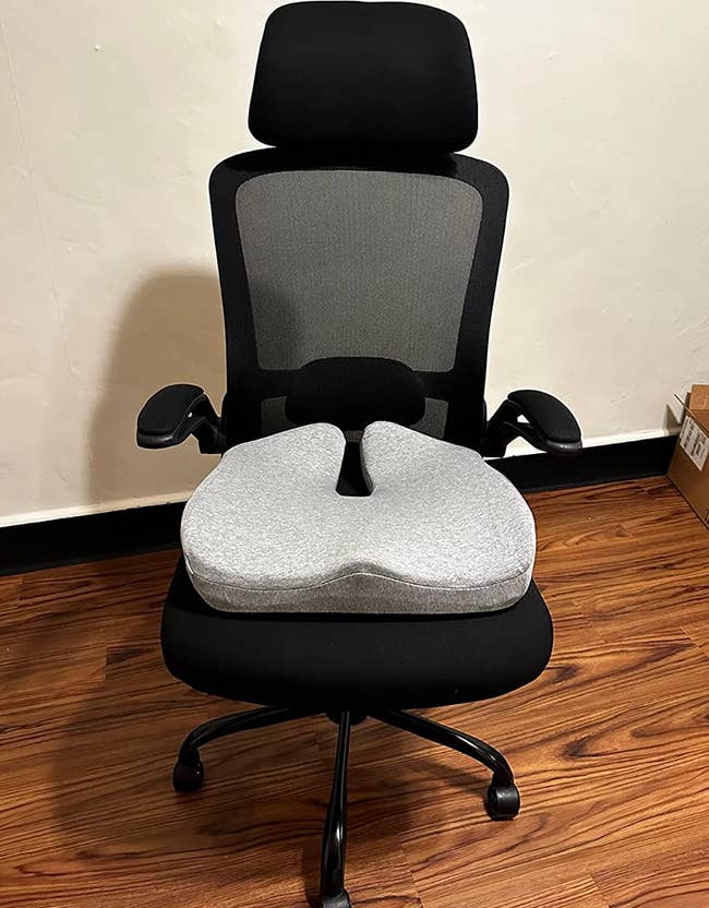 A grey memory foam seat cushion on a swivel chair 