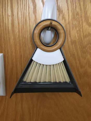 reviewer's mini dustpan and broom hanging on a hook