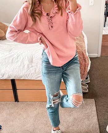 Person in a pink ruffled top and distressed blue jeans