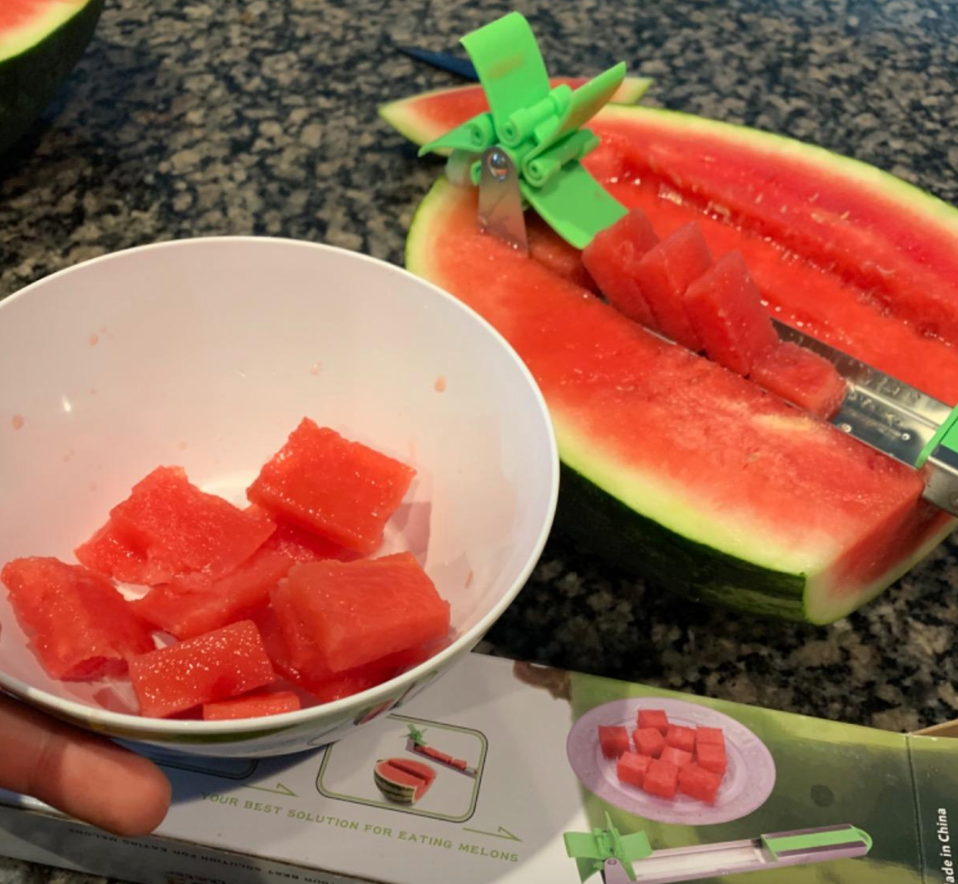 Reviewer using rotating green tool to cut slices from an open watermelon