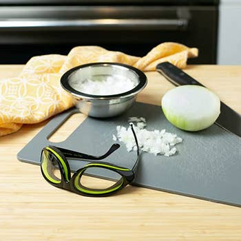 The goggles with arms instead of elastic on a cutting board with onions