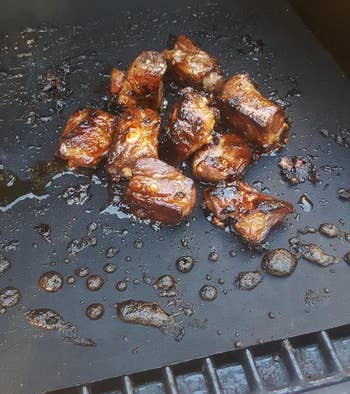reviewer photo of pieces of meat in a sticky sauce cooking on the grill mat