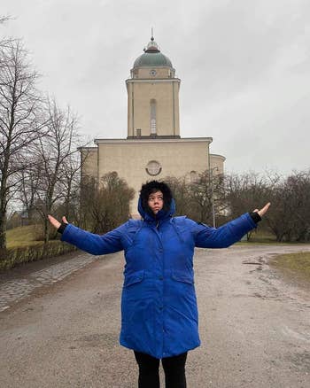 reviewer wearing heavy coat in front of a building in Finland
