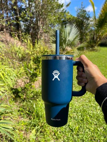 reviewer holding navy blue tumbler with handle