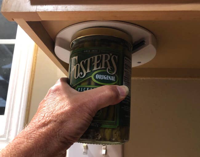 reviewer opening jar of asparagus with under cabinet jar opener