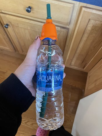 reviewer showing the cap on a water bottle with a straw coming out of it