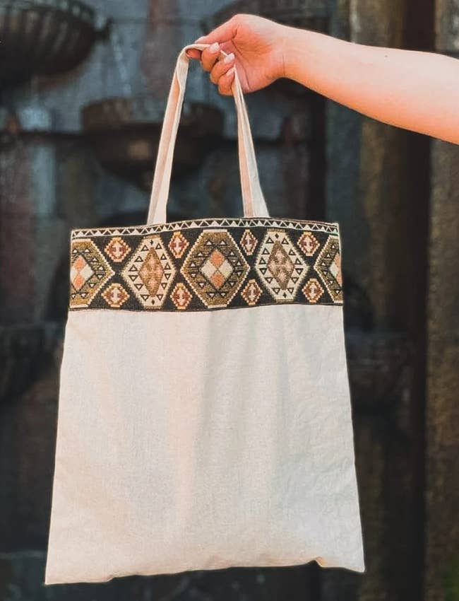 Someone holding a tote with an Armenian design woven at the top of the bag