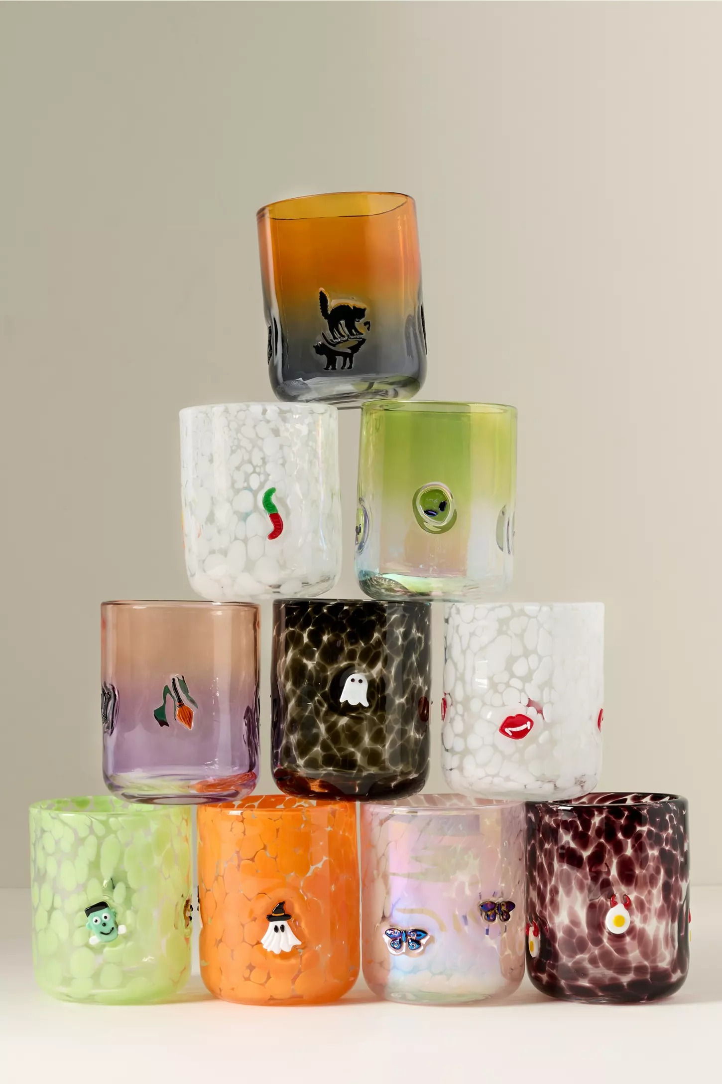 Nine textured drinking glasses stacked successful  a pyramid, each   featuring unsocial   cartoon designs similar  animals, lips, and fruit