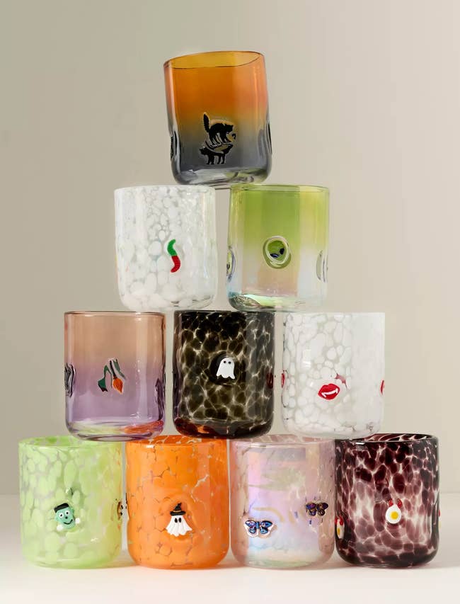 Nine textured drinking glasses stacked successful a pyramid, each featuring unsocial cartoon designs similar animals, lips, and fruit